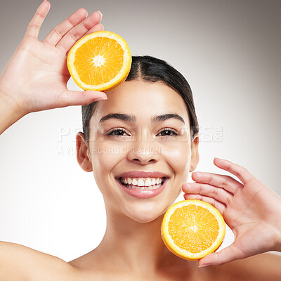 Buy stock photo Young happy beautiful woman holding an orange while posing against a grey studio background alone. One hispanic female smiling showing a fruit while standing against a background