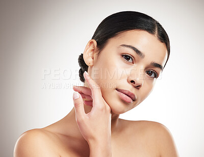 Buy stock photo Portrait of a young mixed race woman touching and feeling her face and posing against a grey studio background. Confident hispanic female posing against a background