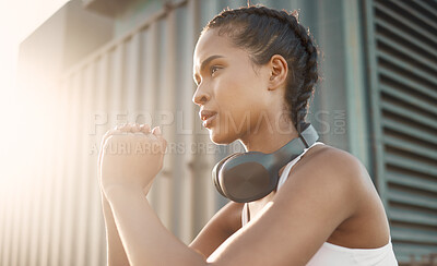 One fit young hispanic woman wearing headphones and doing squat exercises while training in an urban setting outdoors. Focused female athlete doing bodyweight warmup stretches to build muscle, strengthen body and increase endurance for workout