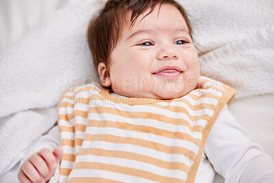Cute little baby playful and smiling while lying on the bed in a bedroom. Small hispanic baby looking around and being curious. Innocent, sweet newborn learning while relaxing in a nursery