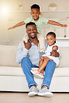Young happy content african american father bonding and relaxing with his little son and daughter sitting on the couch at home. Cheerful small boy and girl playing and spending time with their dad