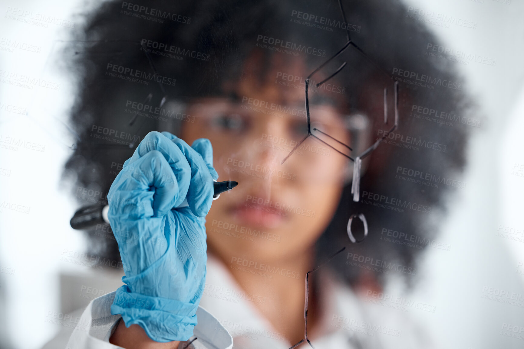 Buy stock photo Closeup of the hand of a young mixed female scientist writing and planning on a board wearing goggles and gloves at work. Focused hispanic lab worker drawing a formula on a board standing at work