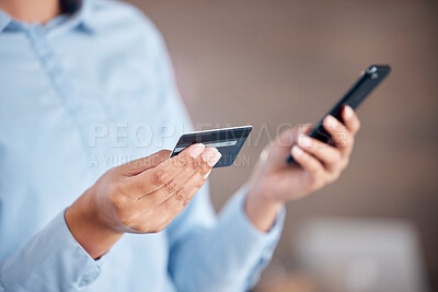 Unrecognizable businesswoman using a phone and credit card standing alone in an office at work. Unrecognizable person shopping online and paying with her card. Using social media on phone
