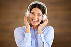 Happy young mixed race businesswoman wearing wireless headphones at work. One female only enjoying listening to relaxing music and songs, audio books or podcast for stress relief while on a break 