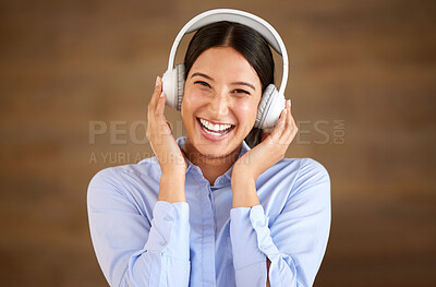 Happy young mixed race businesswoman wearing wireless headphones at work. One female only enjoying listening to relaxing music and songs, audio books or podcast for stress relief while on a break