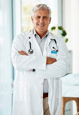 Buy stock photo Experienced mature male doctor smiling and standing with his arms crossed in a hospital. One optimistic senior man wearing a lab coat looking confident and happy to give a patient good news