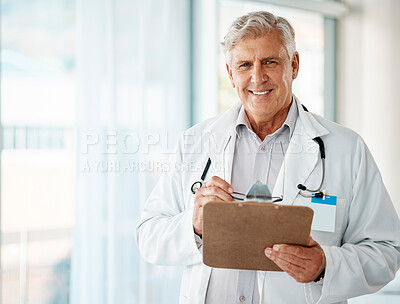 Confident mature male doctor reading patient records on clipboard in hospital or clinic. One happy senior caucasian man in white coat. Trusted medical physician and practitioner working in healthcare