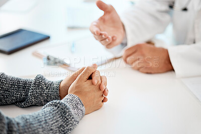 Buy stock photo Above closeup of hands during a consult between a caucasian man doctor and male patient at a table in the clinic. Mixed race patient with clasped hands receiving advice from his doctor about medical health and wellness at a hospital