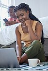 Young african american man and woman sitting in the bedroom smiling and using wireless devices. Black couple using a laptop and phone on a weekend while enjoying coffee and quiet time at home