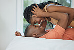 Happy and romantic african american couple lying in bed together at home and being intimate. Playful black boyfriend and girlfriend bonding together with their foreheads touching. Love and passion