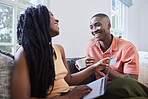 Happy young african american couple talking and bonding while sitting at home. Handsome man drinking coffee while girlfriend shops online. Smiling woman holding credit card and laptop to do payment