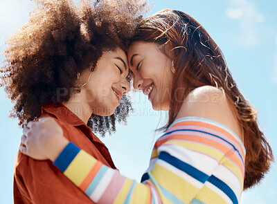 Buy stock photo Close up of two young mixed race female couple embracing each other and smiling outside on a sunny day. A Beautiful gay hispanic woman with a cool afro hair style showing affection by hugging her girlfriend while on a date