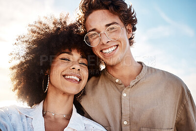 Buy stock photo Portrait of a young  mixed race couple enjoying a day at the beach looking happy and in love