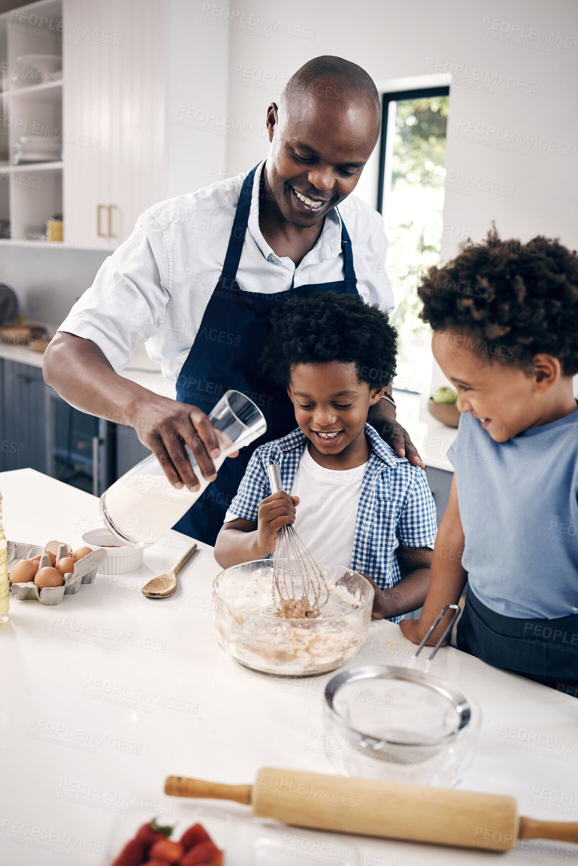 Buy stock photo Adorable African American little boy with afro baking in the kitchen at home with his dad and brother.  Cheerful Black man holding milk and mixing ingredients while bonding with his little boys
