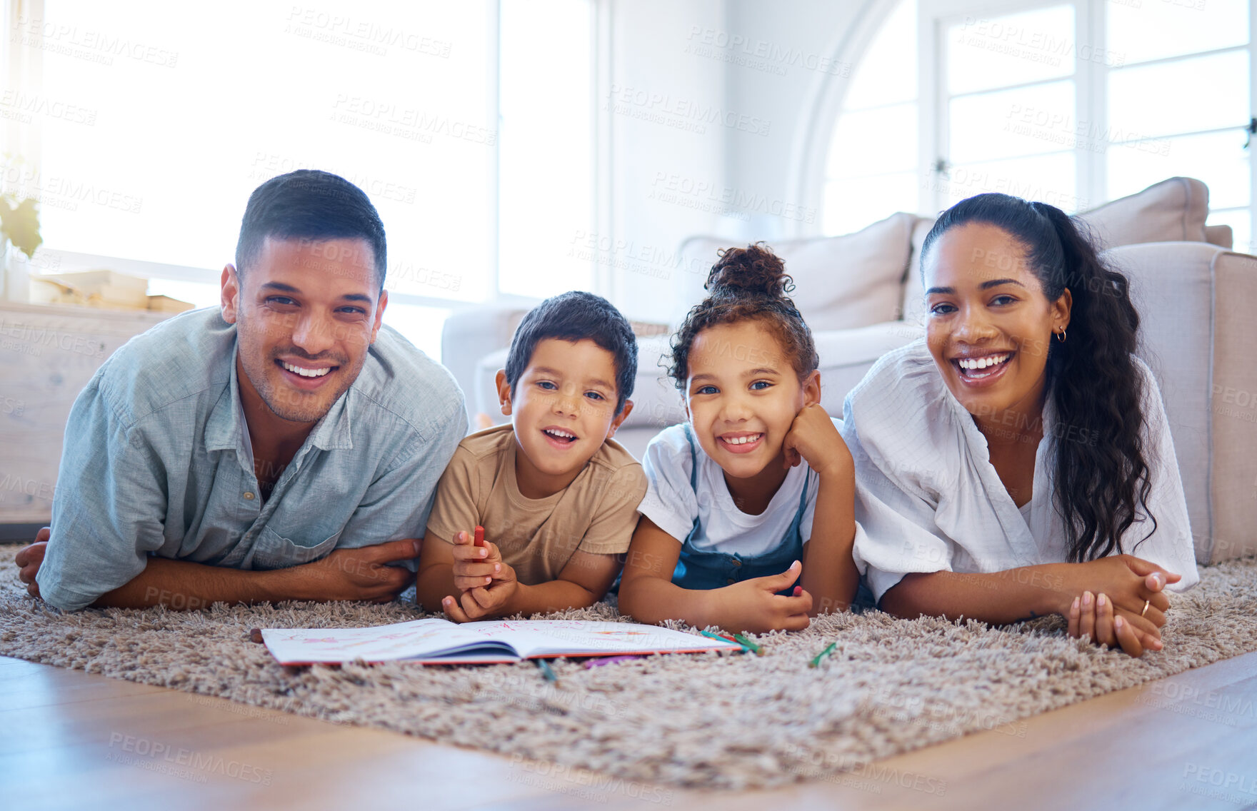Buy stock photo Portrait of a smiling young mixed race family lying close together on the living room floor at home. Happy adorable hispanic son and daughter bonding with their mother and father during a weekend