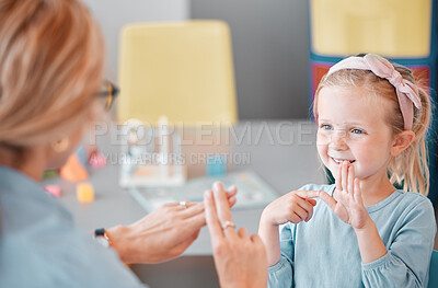 Buy stock photo Happy kid, communication and sign language smiling child practicing asl with teacher at school. Person with a disability, hearing or educator showing finger gesture to young little girl in classroom