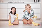 Portrait of a smiling young caucasian woman kneeling and scrubbing the floor with her daughter. Adorable little girl helping her mother with housework and chores. Teaching children healthy habits