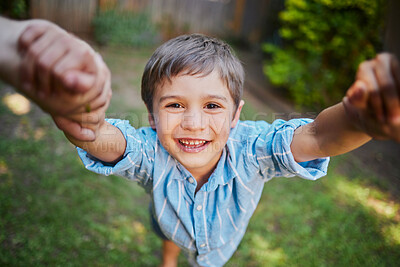 The moment of lifting the son up holding his hands by mom and dad while outside in the backyard. Young happy boy having fun and smiling while being lifted by two hands on a sunny day