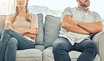 Angry caucasian married couple sitting on couch arms folded to avoid fight. Couple in conflict distanced on sofa. Frustrated couple sitting apart on a couch. Unhappy couple in therapy on sofa together