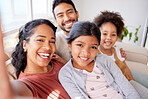 Closeup portrait of a beautiful african american woman taking selfies with her husband and two daughters in the living room at home. A young wife taking photos with her mixed race family on the sofa