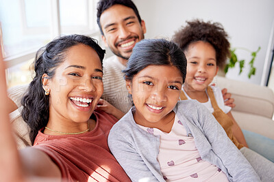 Buy stock photo Closeup portrait of a beautiful african american woman taking selfies with her husband and two daughters in the living room at home. A young wife taking photos with her mixed race family on the sofa