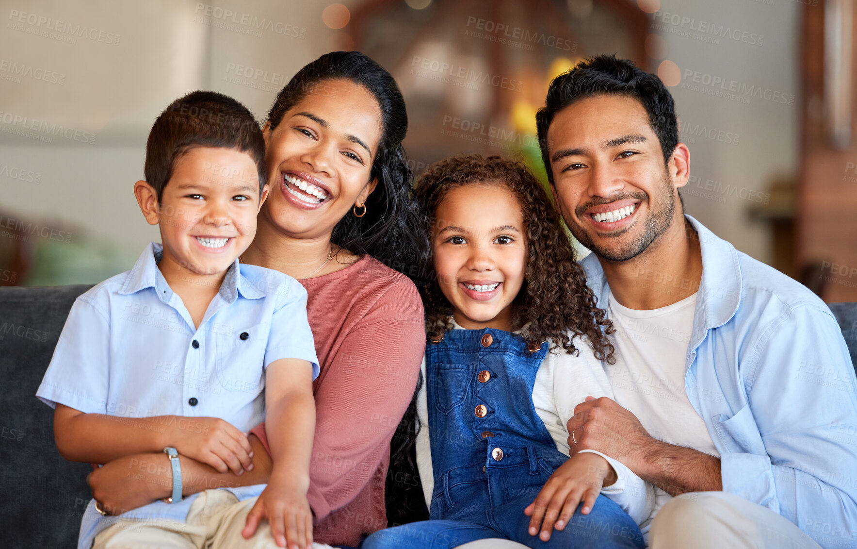 Buy stock photo Portrait of a smiling couple with little kids at home. Mixed race mother and father bonding with their son and daughter on a weekend inside. Hispanic boy and girl enjoying free time with their parents