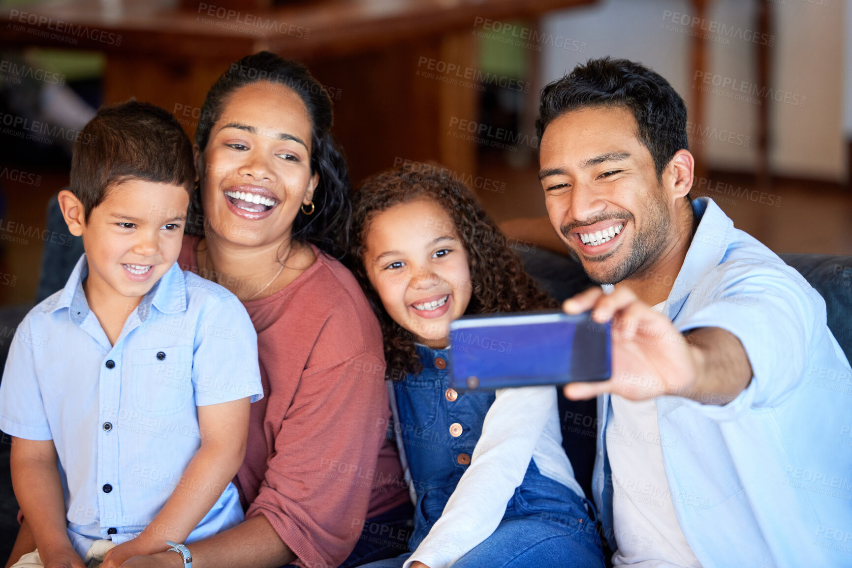 Buy stock photo Young hispanic family taking a selfie with a phone together at home. Father taking a photo with his children and wife smiling. Mixed race family making memories and taking pictures 