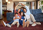Happy family in their new house. Cheerful family with two kids sitting on carpet, mom and dad making roof shape with hands over heads during relocation. Safe and protected with insurance 