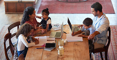 Buy stock photo Young mixed race family sitting at a table while working on a laptop and spending time together at home. Young hispanic children doing homework while their parents work remotely 