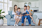 Caucasian family reading a book together on the couch at home. Mother and father teaching their little son and daughter how to read. Brother and sister learning their alphabet with their parents