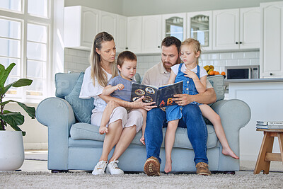 Buy stock photo Caucasian family reading a book together on the couch at home. Mother and father teaching their little son and daughter how to read. Brother and sister learning their alphabet with their parents