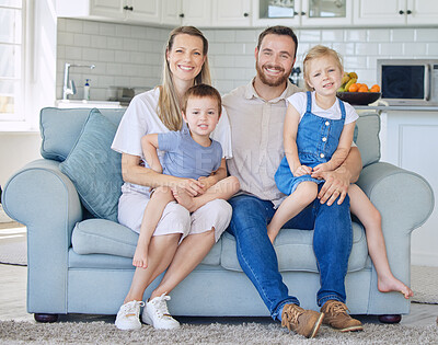 Buy stock photo Happy and cheerful caucasian family with two kids smiling while sitting on couch together at home. Loving parents bonding with their adorable little son and daughter