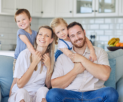 Buy stock photo Happy and cheerful caucasian family of four smiling while relaxing together at home. Carefree loving parents bonding with their cute little son and daughter. Siblings hugging their mother and father 