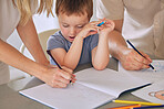 Mother and father teaching little son during homeschool class at home. Autistic cute little caucasian boy learning how to read and write while his parents help him. Couple tutoring math to a child