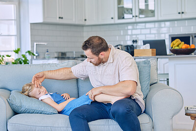 Caucasian father using his hand to feel the high body temperature on his sick little daughter\'s forehead for symptoms of fever, flu or covid. Worried parent caring for ill child lying on sofa at home