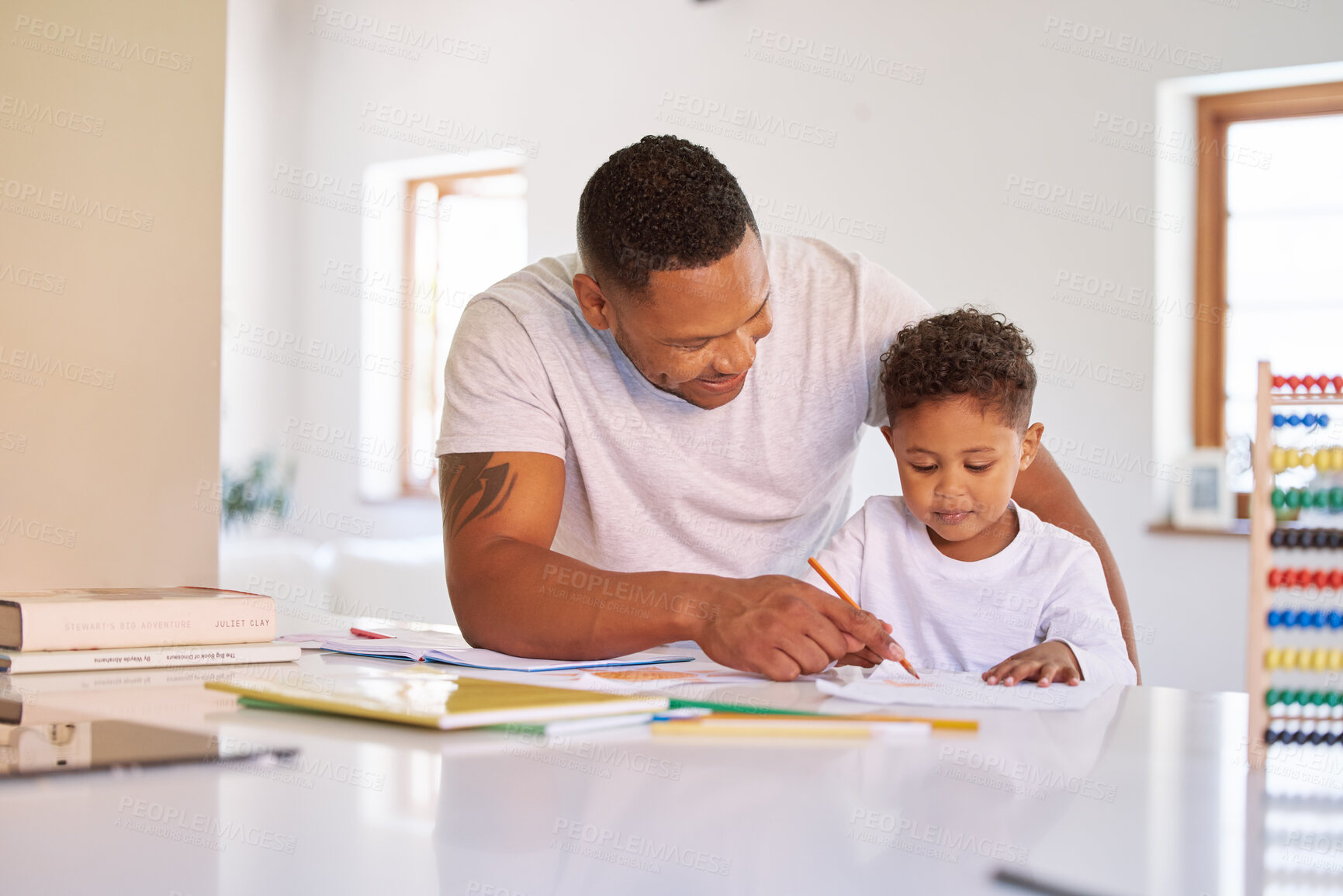 Buy stock photo Mixed race boy learning and studying in homeschool with dad. Man helping his son with homework and assignments at home. Parent teaching child to colour and write at home during lockdown