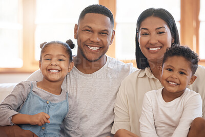 Buy stock photo Portrait of a smiling young family of four at home. Mixed race mother and father bonding with their son and daughter on a weekend inside. Hispanic boy and girl enjoying free time with their parents