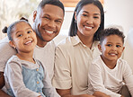 Portrait of a smiling couple with little kids at home. Mixed race mother and father bonding with their son and daughter on a weekend inside. Hispanic boy and girl enjoying free time with their parents