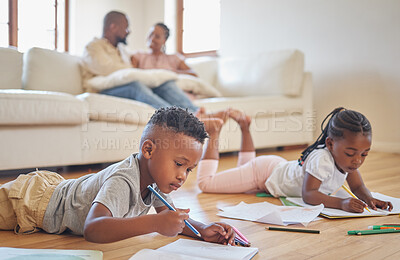 Little boy and girl drawing with colouring pencils lying on living room floor with their parents relaxing on couch. Little children sister and brother siblings colouring in during family time at home