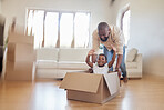 Cheerful african american father pushing excited little girl around in carton box, riding around and having fun in living room. Happy dad and daughter enjoying moving day at their new home