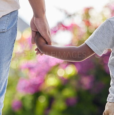 Closeup of little boy holding dads hand with nature background. African american family holding hands showing love, support and affection. A parent gives a child guidance and keep him safe