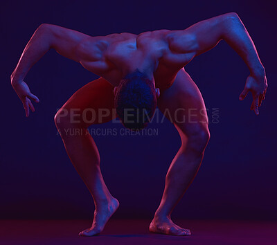 An unknown muscular man showing his athletic shape while standing against a dark background with wide copyspace. Strong fit male flexing his muscles under a blue and purple light