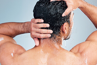 Buy stock photo Closeup of muscular man washing his hair while taking a shower against a blue background. Fit and strong mixed race man standing under pouring water. Hygiene and body care routine