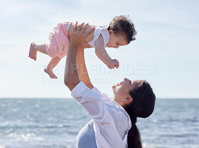 Mother lifting a baby. Mother and daughter on holiday by the ocean. Happy mother playing with her child. Baby girl bonding with her parent. Parent on vacation with her little girl.