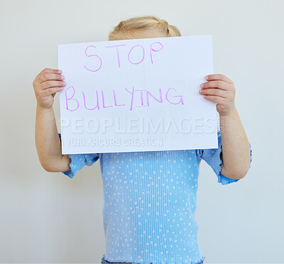 Buy stock photo Little girl holding a paper with message that bullying at school must be stopped. Blonde child actively protest against bullying, kid starting an anti bully campaign against white copyspace background