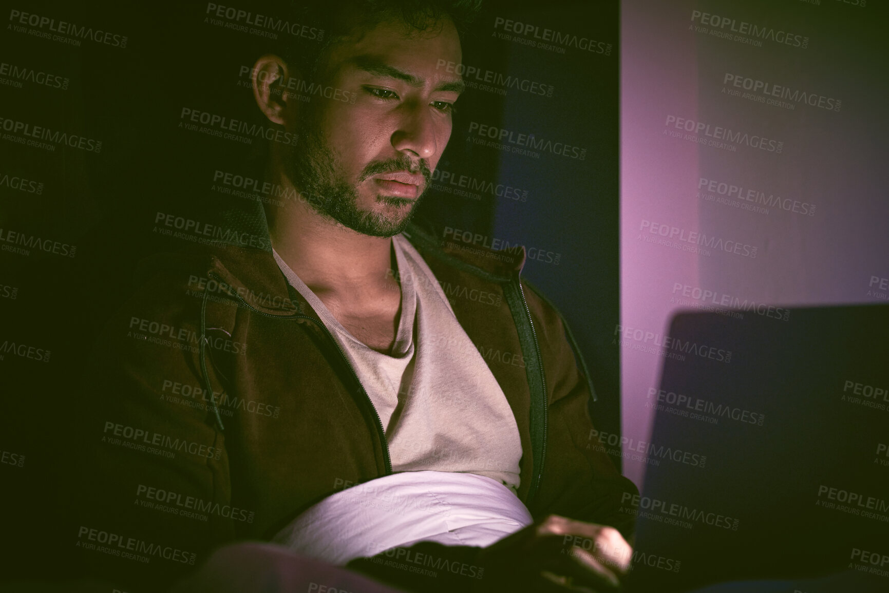 Buy stock photo Asian man with mental disorder sitting alone at night and feeling hopeless while searching for a job on a laptop. Mixed race unemployed male feeling depressed and stressed, overwhelmed student
