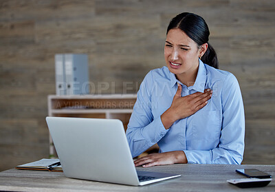 Young hispanic woman suffering from chest pain in office. Mixed race businesswoman feeling unwell while using a laptop at work