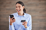Young mixed race happy businesswoman using a credit card and phone to shop online at work. One hispanic woman paying for a purchase using her phone. Woman buying products using her phone and bank card