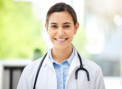 Buy stock photo Confident young mixed race female doctor standing and smiling inside a medical office. One hispanic woman in a white coat with stethoscope. Trusted practitioner caring for the health of patients