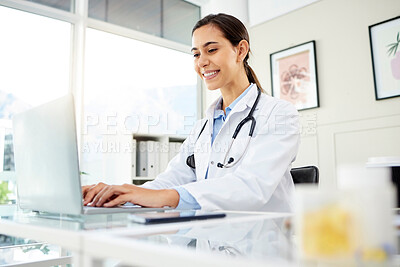 Closeup of a young mixed race female doctor using a laptop and smiling at work. Hispanic health care worker typing an email in a office at the hospital
